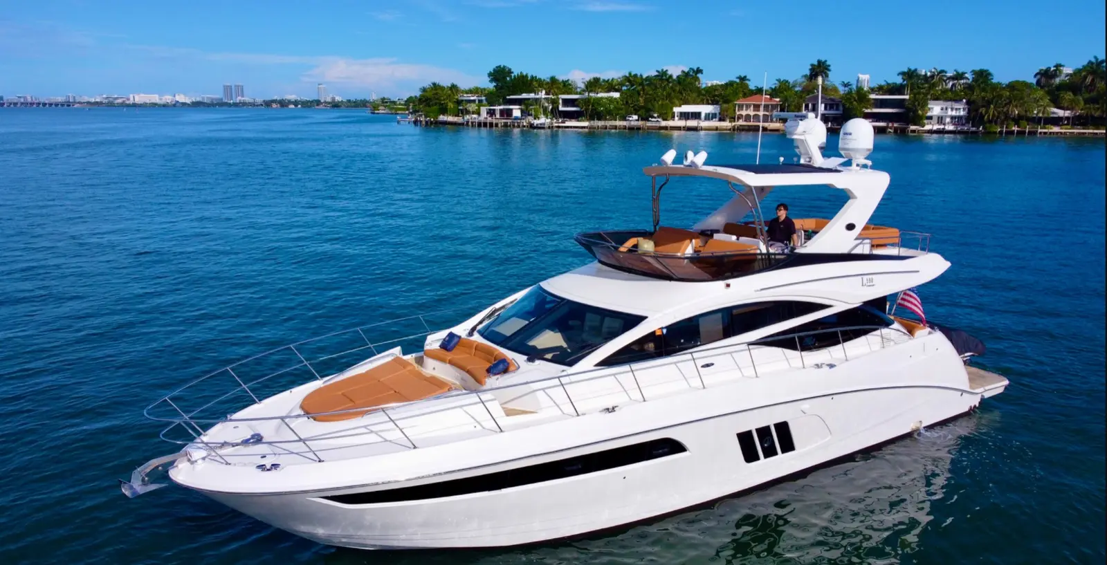 Sea Ray 64 flybridge yacht cruising past Miami waterfront homes
